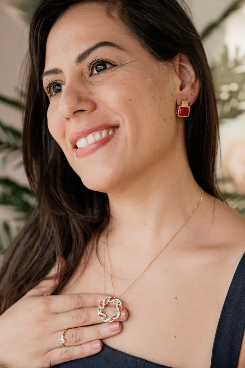 Cliente sorrindo, mão no colar, no showroom Di Firenze